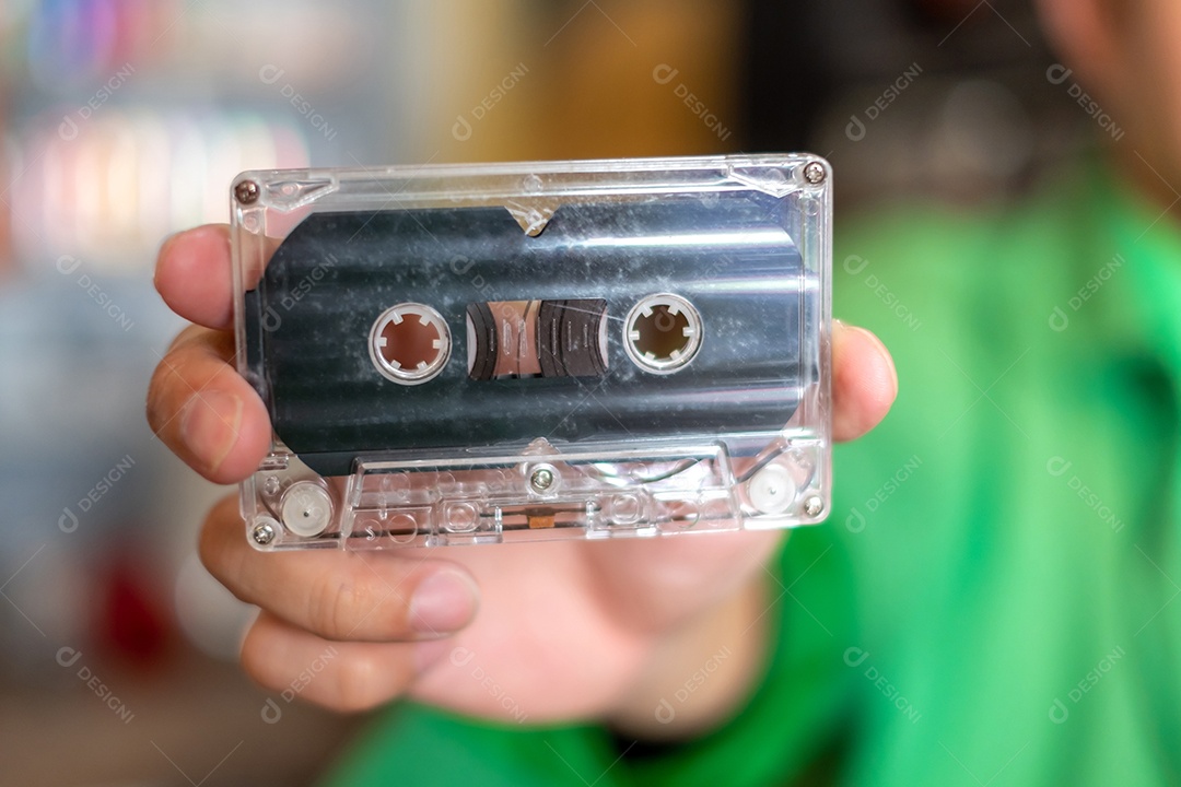 O homem da mão segurando fita cassete de áudio antiga, fitas de músicas dos anos 80 e cassetes de música estéreo.