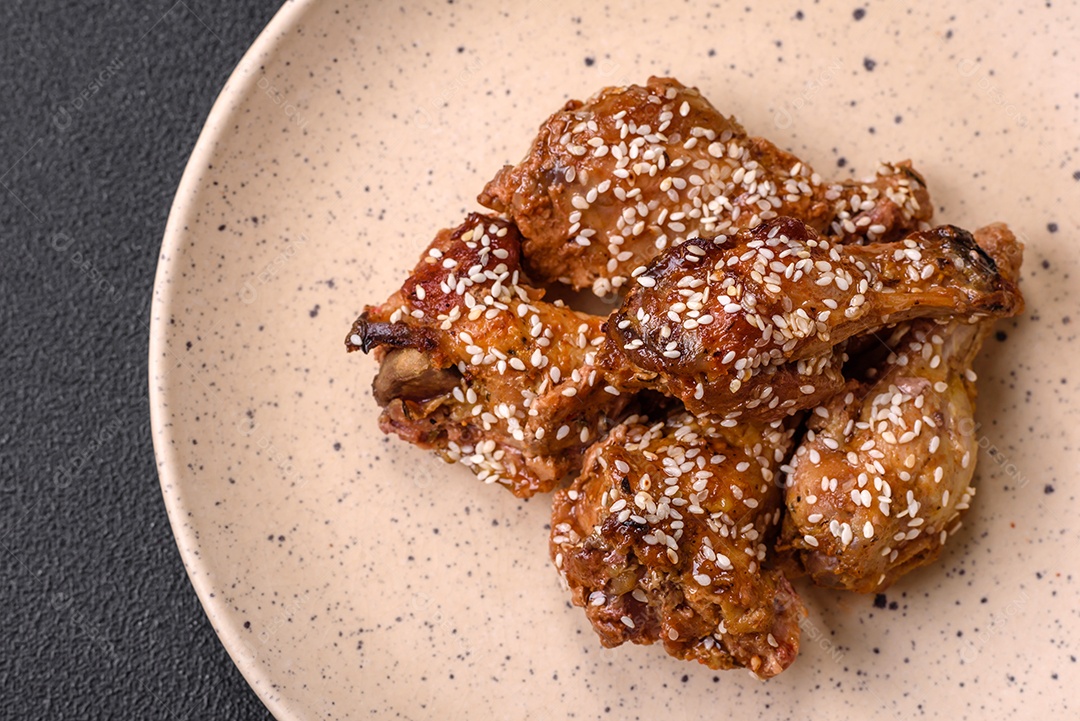 Salada quente com vitela, tomate, pimentão, abobrinha, gergelim, sal, especiarias e ervas sobre fundo escuro de concreto