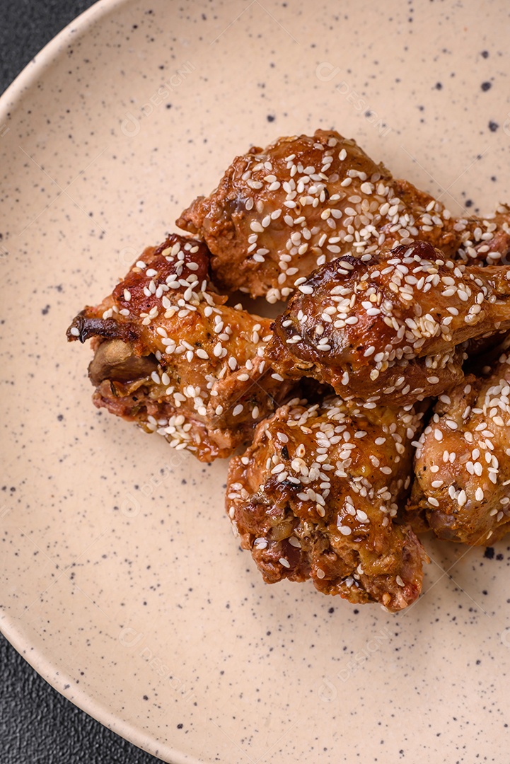Salada quente com vitela, tomate, pimentão, abobrinha, gergelim, sal, especiarias e ervas sobre fundo escuro de concreto