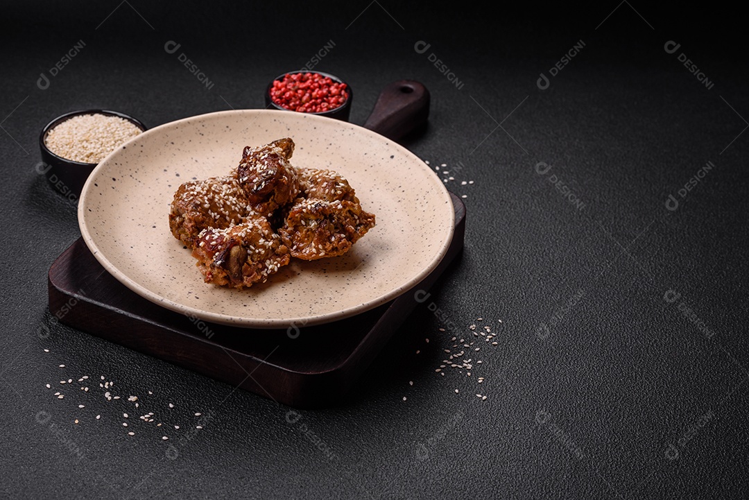 Deliciosas asas de frango grelhado com sal, especiarias e molho teriyaki sobre um fundo escuro de concreto