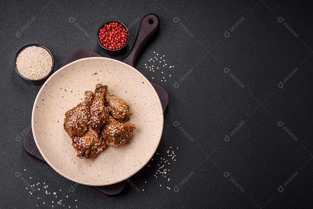 Deliciosas asas de frango grelhado com sal, especiarias e molho teriyaki sobre um fundo escuro de concreto