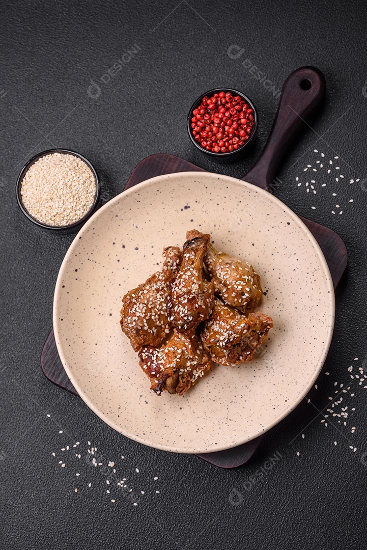 Deliciosas asas de frango grelhado com sal, especiarias e molho teriyaki sobre um fundo escuro de concreto