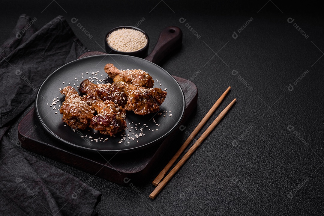 Deliciosas asas de frango grelhado com sal, especiarias e molho teriyaki sobre um fundo escuro de concreto