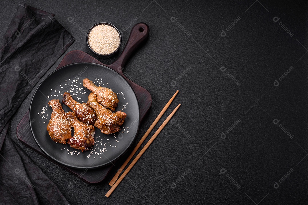 Deliciosas asas de frango grelhado com sal, especiarias e molho teriyaki sobre um fundo escuro de concreto