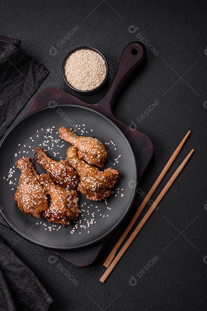 Deliciosas asas de frango grelhado com sal, especiarias e molho teriyaki sobre um fundo escuro de concreto