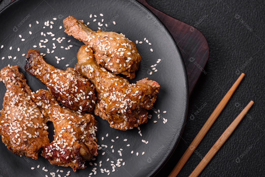 Deliciosas asas de frango grelhado com sal, especiarias e molho teriyaki sobre um fundo escuro de concreto