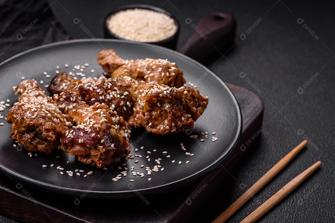 Deliciosas asas de frango grelhado com sal, especiarias e molho teriyaki sobre um fundo escuro de concreto