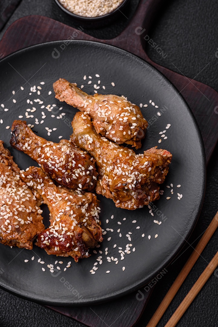 Deliciosas asas de frango grelhado com sal, especiarias e molho teriyaki sobre um fundo escuro de concreto