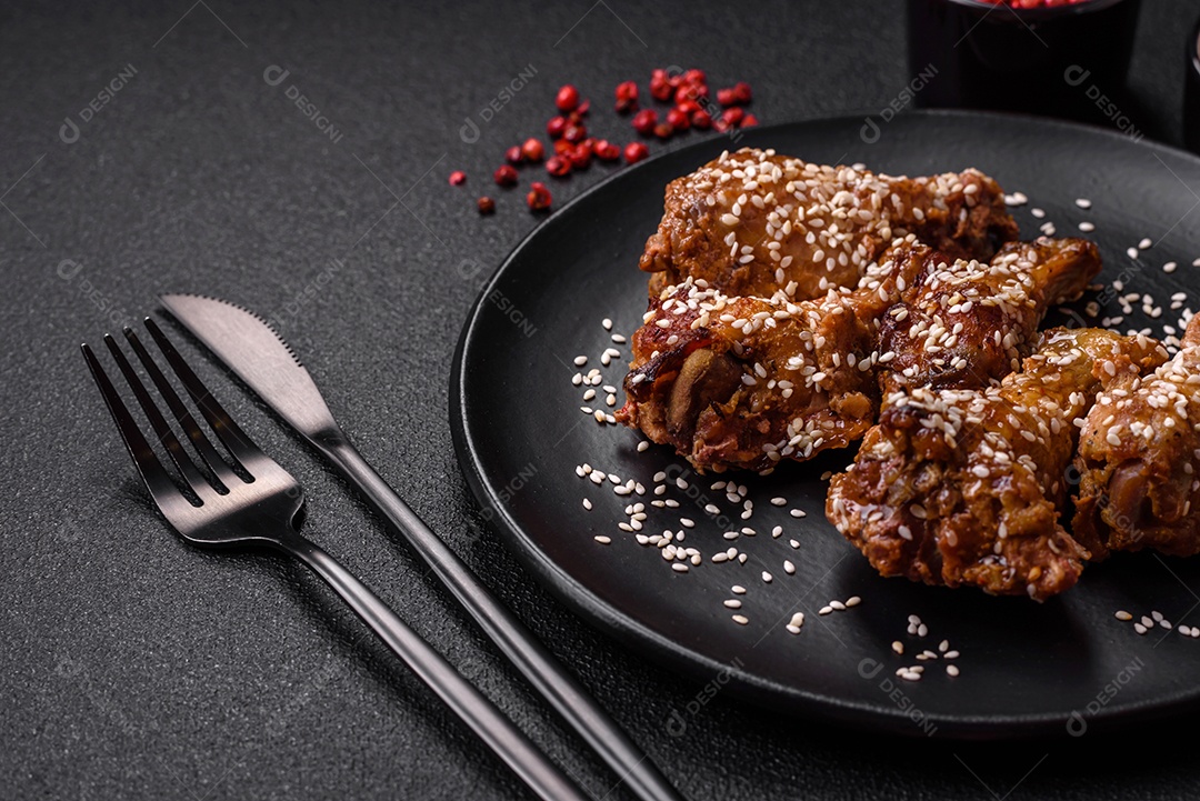 Deliciosas asas de frango grelhado com sal, especiarias e molho teriyaki sobre um fundo escuro de concreto