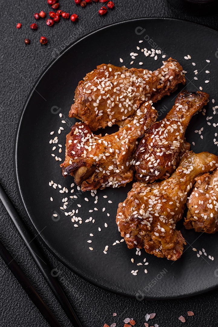 Deliciosas asas de frango grelhado com sal, especiarias e molho teriyaki sobre um fundo escuro de concreto