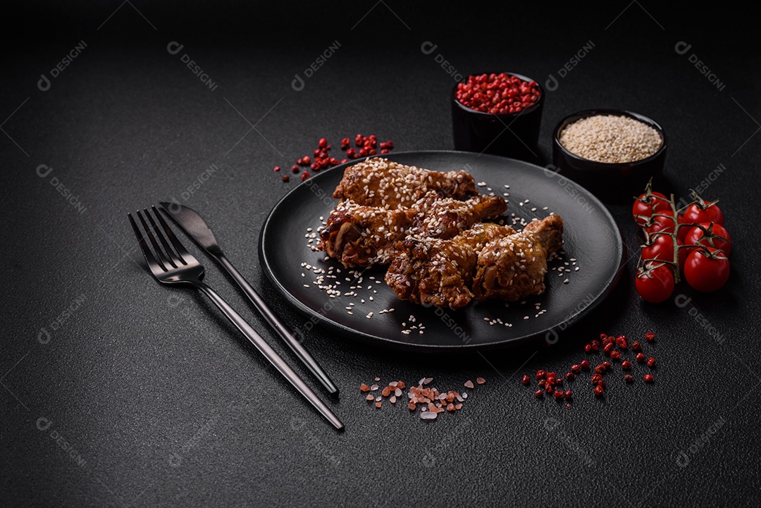 Deliciosas asas de frango grelhado com sal, especiarias e molho teriyaki sobre um fundo escuro de concreto