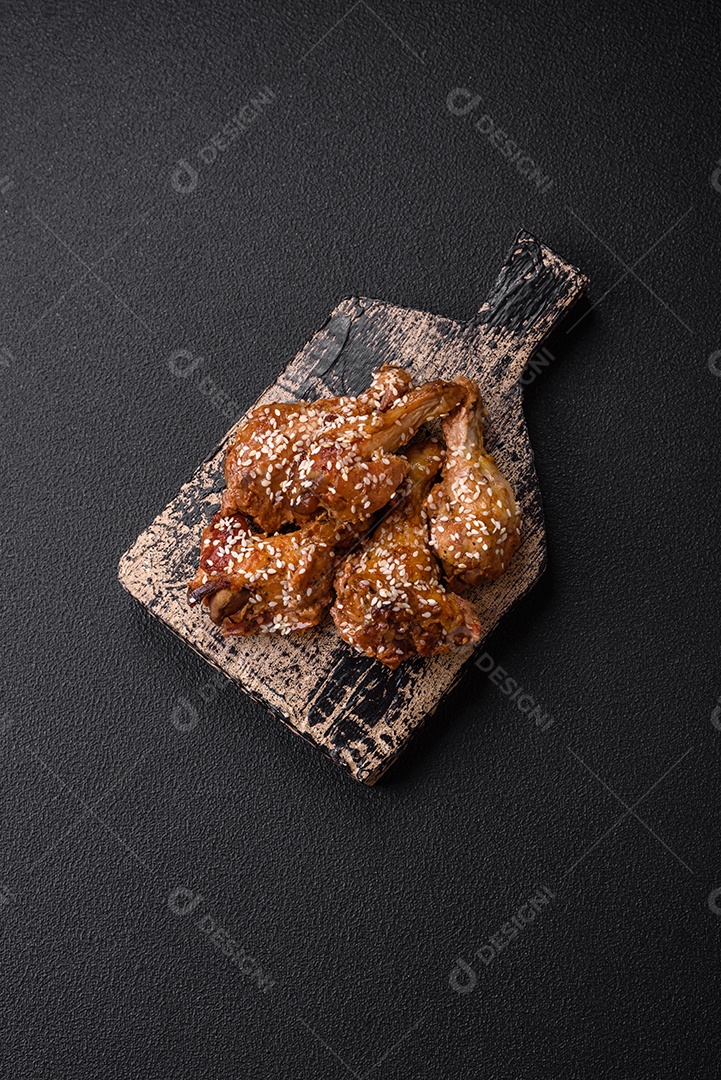 Deliciosas asas de frango grelhado com sal, especiarias e molho teriyaki sobre um fundo escuro de concreto
