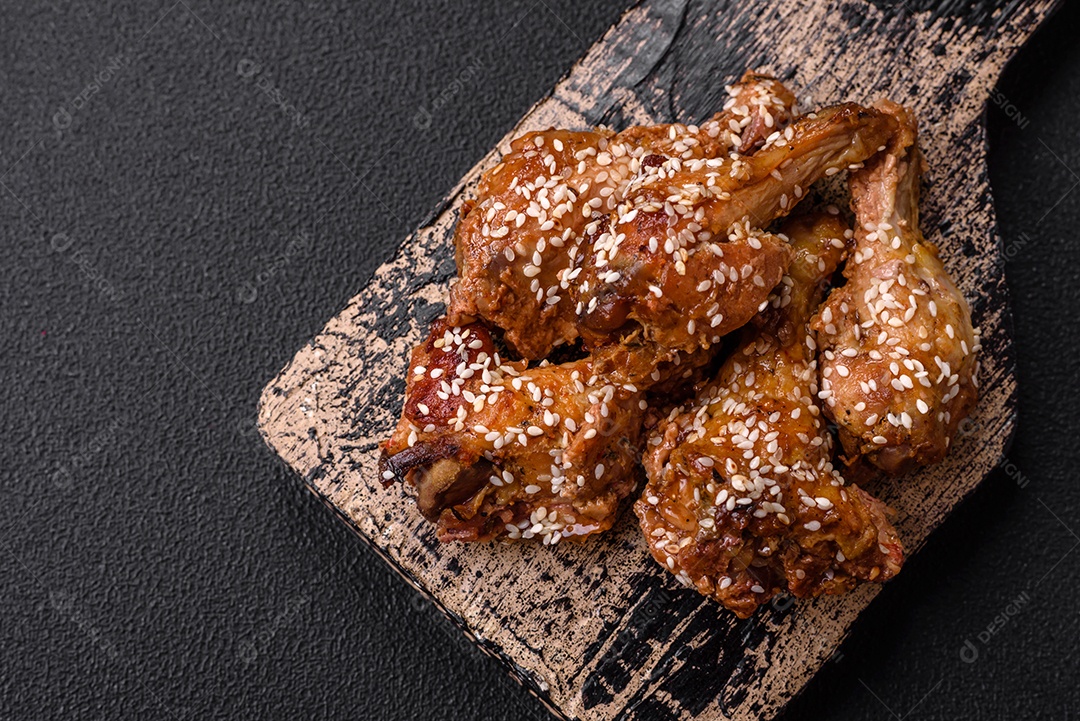 Deliciosas asas de frango grelhado com sal, especiarias e molho teriyaki sobre um fundo escuro de concreto