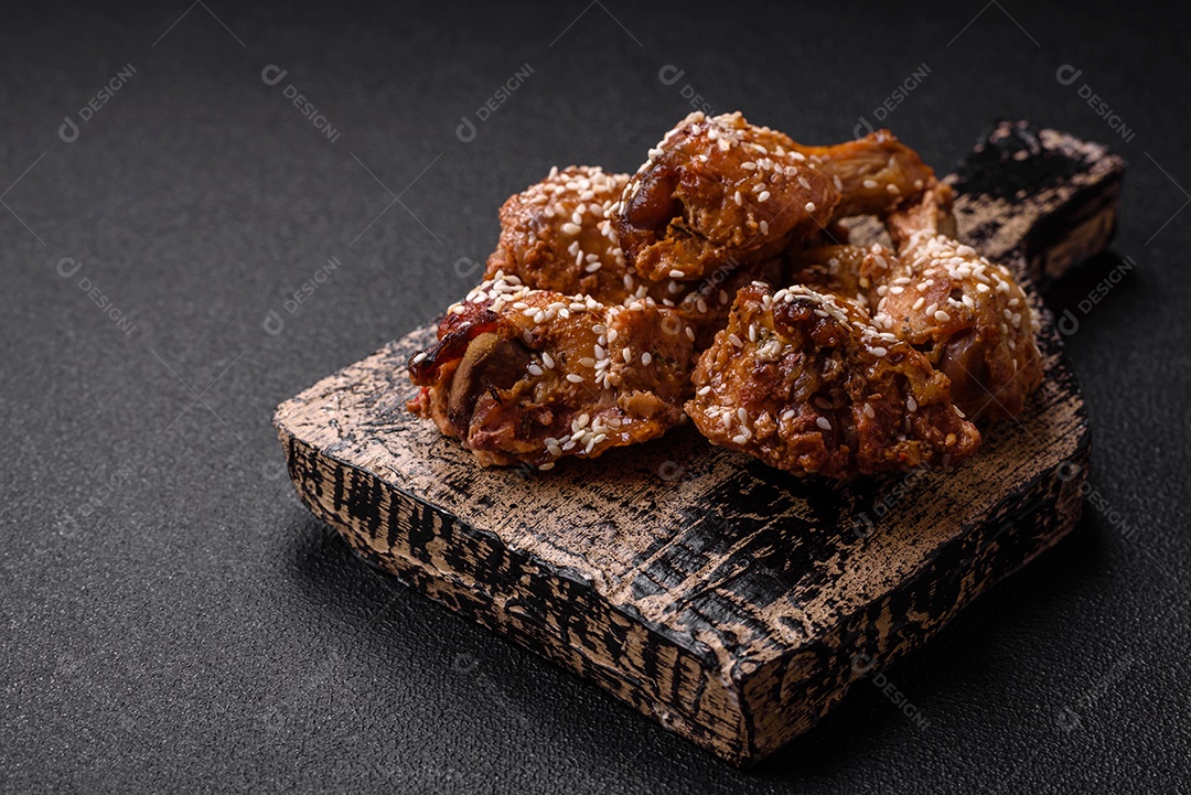 Deliciosas asas de frango grelhado com sal, especiarias e molho teriyaki sobre um fundo escuro de concreto