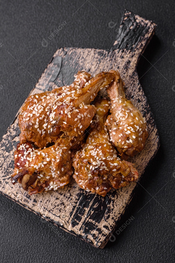 Deliciosas asas de frango grelhado com sal, especiarias e molho teriyaki sobre um fundo escuro de concreto