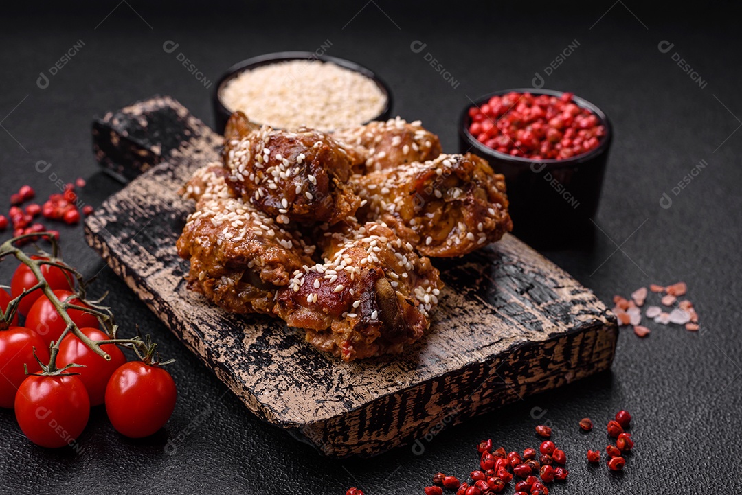 Deliciosas asas de frango grelhado com sal, especiarias e molho teriyaki sobre um fundo escuro de concreto