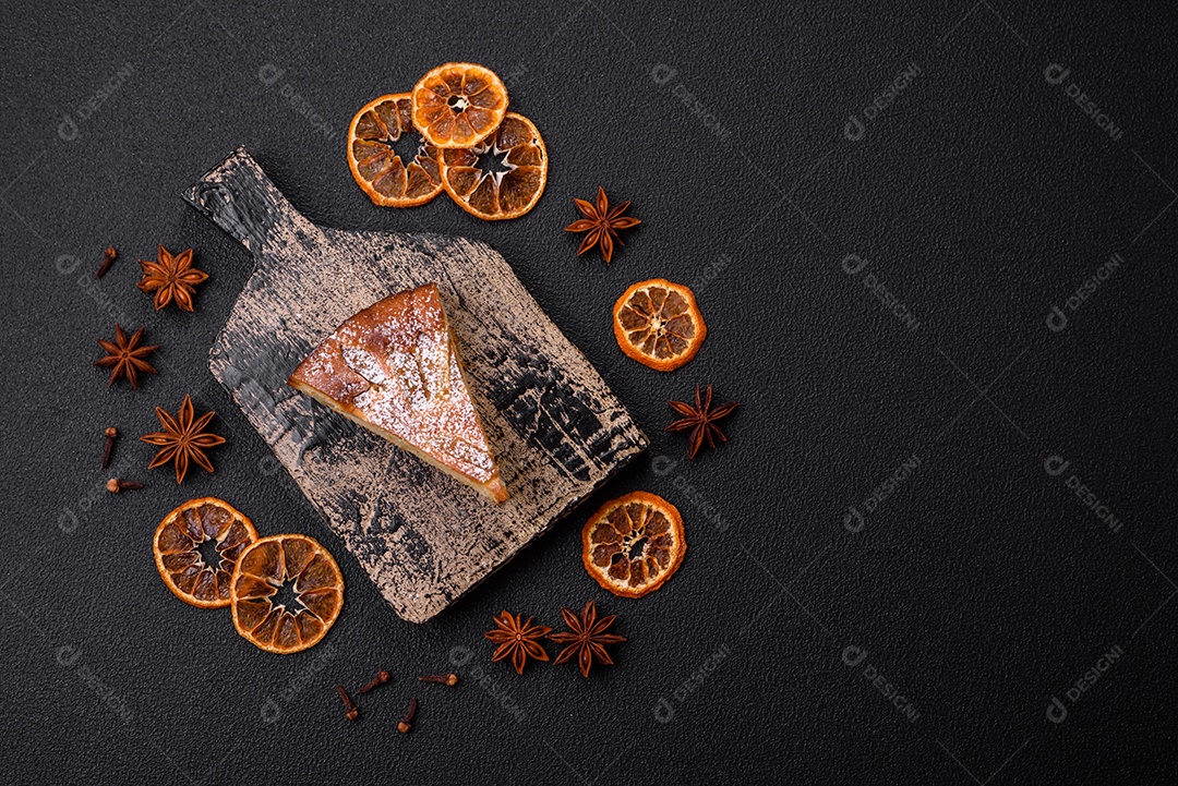 Um pedaço de torta caseira assada com maçã ou pêra, com canela, polvilhada com pó sobre um fundo escuro de concreto
