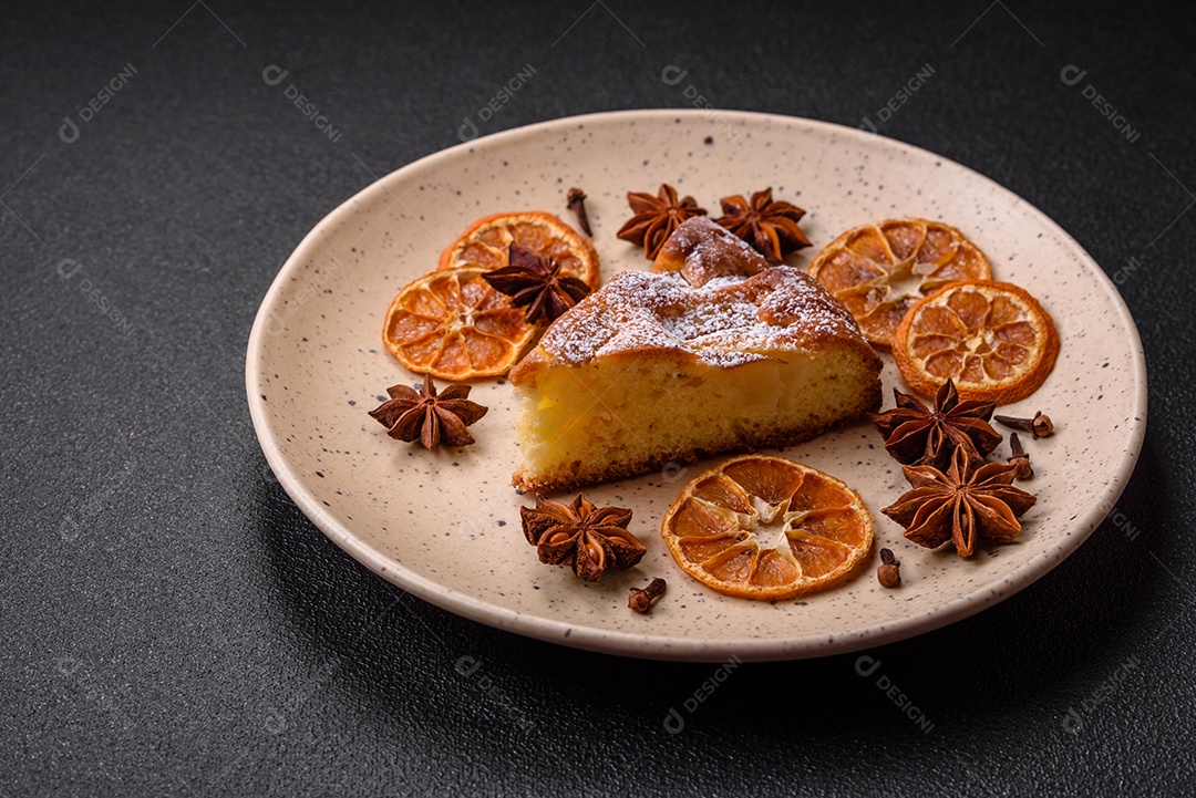 Um pedaço de torta caseira assada com maçã ou pêra, com canela, polvilhada com pó sobre um fundo escuro de concreto