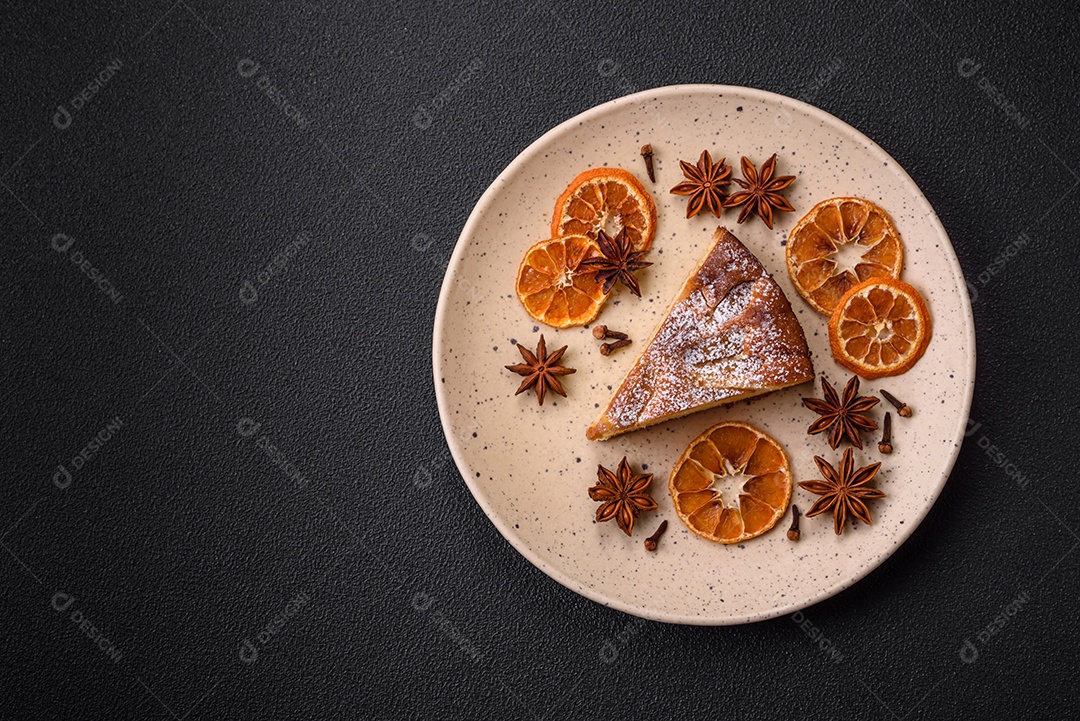 Um pedaço de torta caseira assada com maçã ou pêra, com canela, polvilhada com pó sobre um fundo escuro de concreto