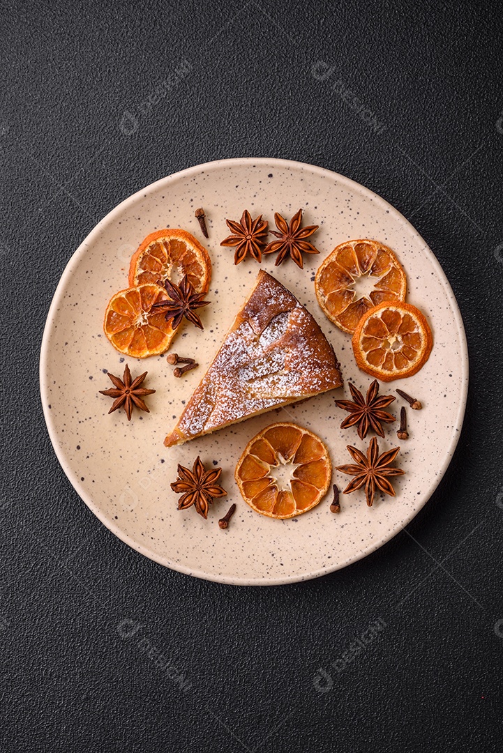 Um pedaço de torta caseira assada com maçã ou pêra, com canela, polvilhada com pó sobre um fundo escuro de concreto