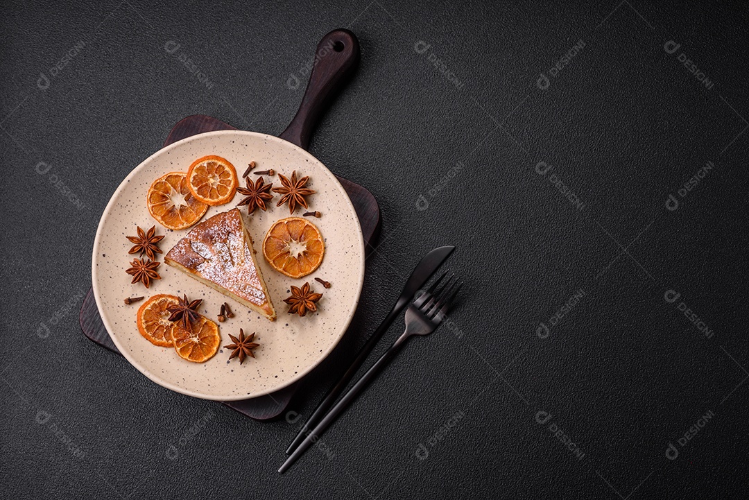 Um pedaço de torta caseira assada com maçã ou pêra, com canela, polvilhada com pó sobre um fundo escuro de concreto