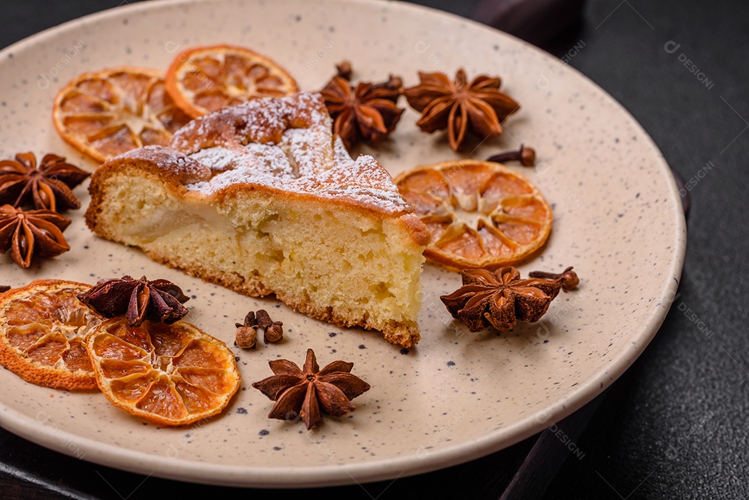 Um pedaço de torta caseira assada com maçã ou pêra, com canela, polvilhada com pó sobre um fundo escuro de concreto