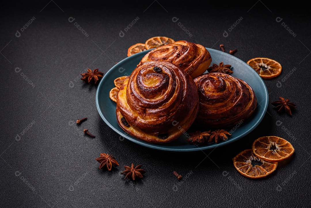 Deliciosos rolos de passas de canela assados ​​em forma de rolos sobre um fundo escuro de concreto