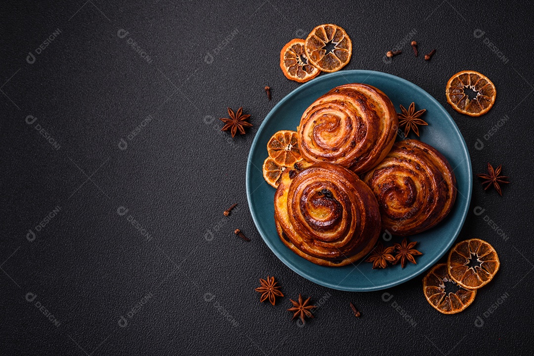 Deliciosos rolos de passas de canela assados ​​em forma de rolos sobre um fundo escuro de concreto