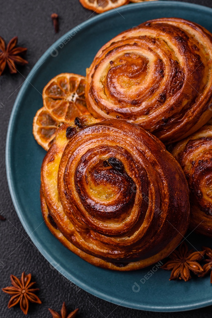 Deliciosos rolos de passas de canela assados ​​em forma de rolos sobre um fundo escuro de concreto
