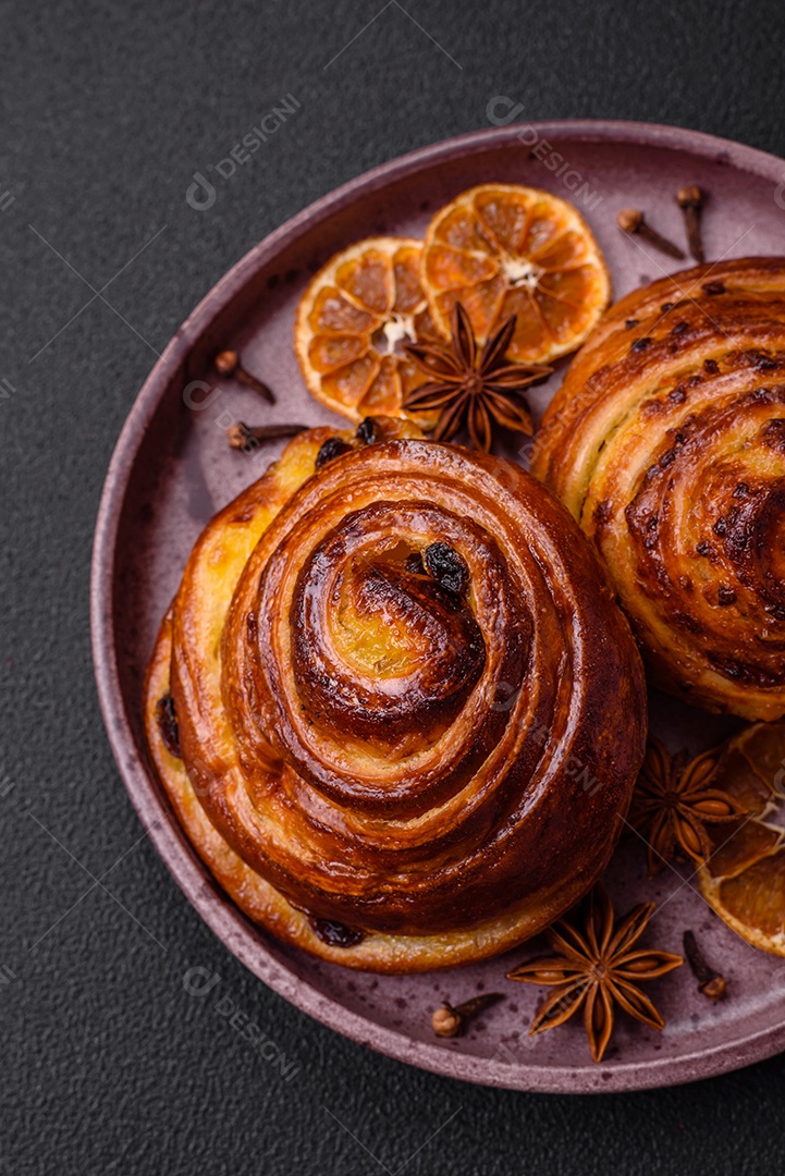 Deliciosos rolos de passas de canela assados ​​em forma de rolos sobre um fundo escuro de concreto
