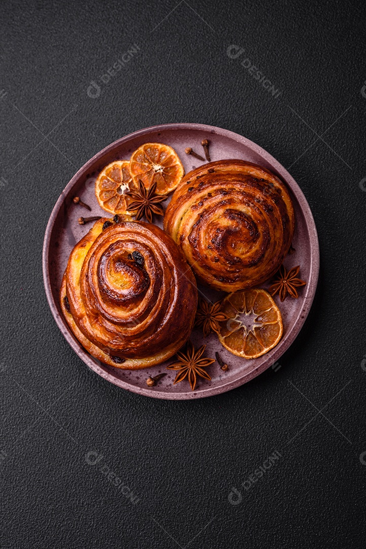 Deliciosos rolos de passas de canela assados ​​em forma de rolos sobre um fundo escuro de concreto