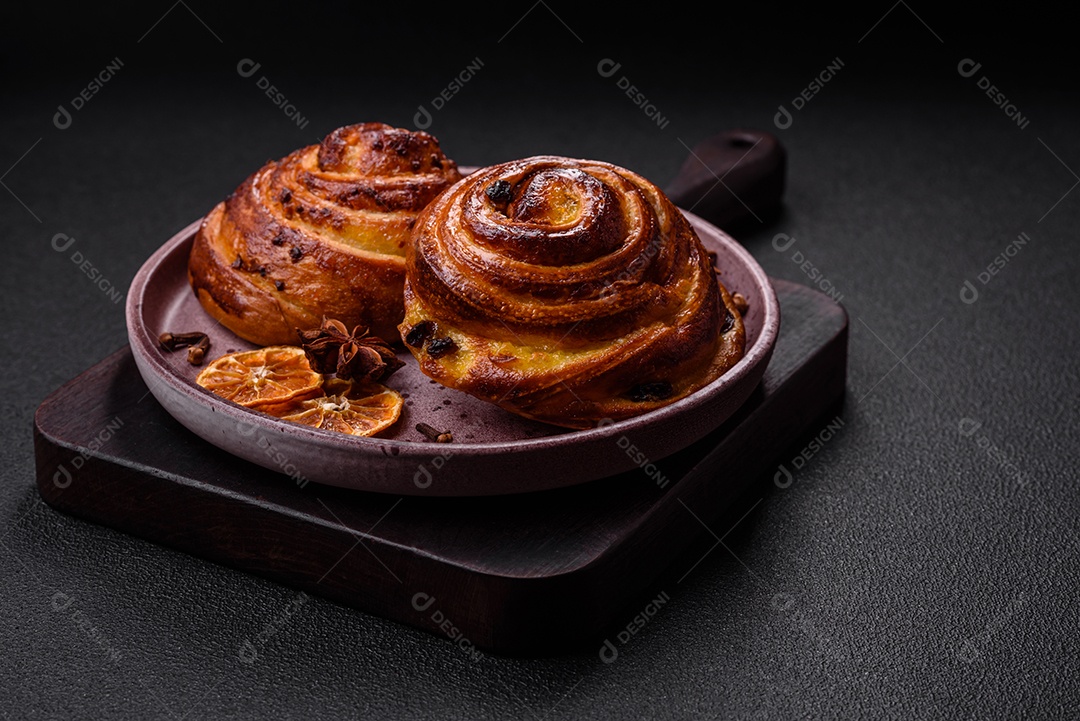 Deliciosos rolos de passas de canela assados ​​em forma de rolos sobre um fundo escuro de concreto