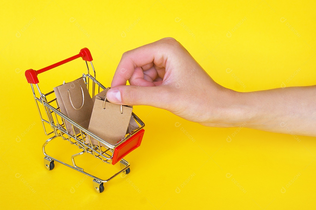 Mão pegando sacolas de compra de dentro do carrinho