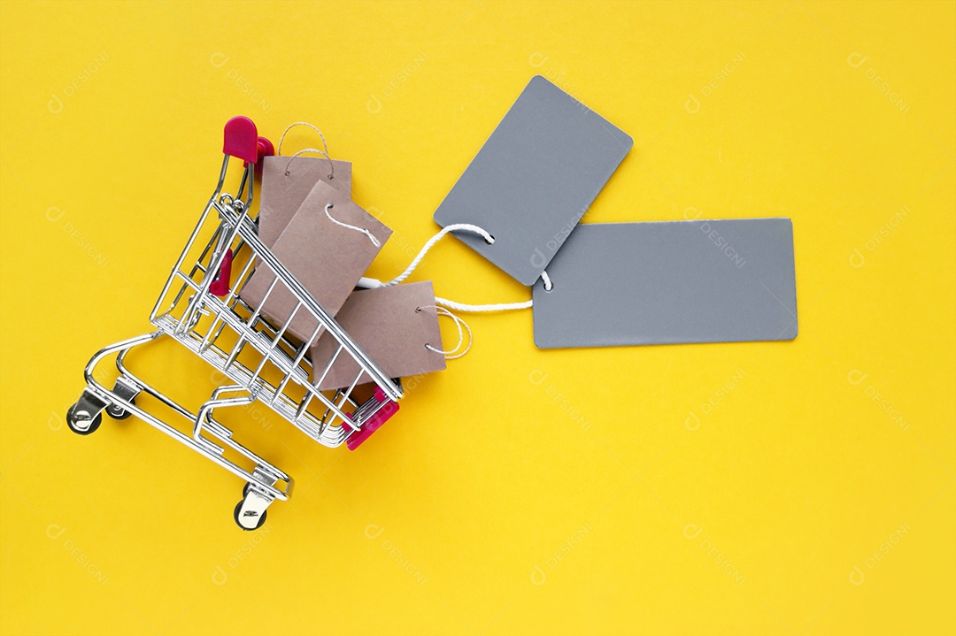 Mini carrinho de compras com sacolinhas kraft e etiquetas sobre fundo amarelo