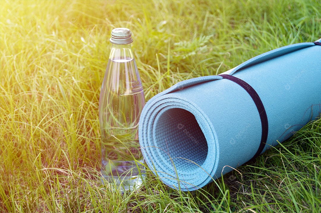 Tapete de ioga e garrafa de água sobre gramado