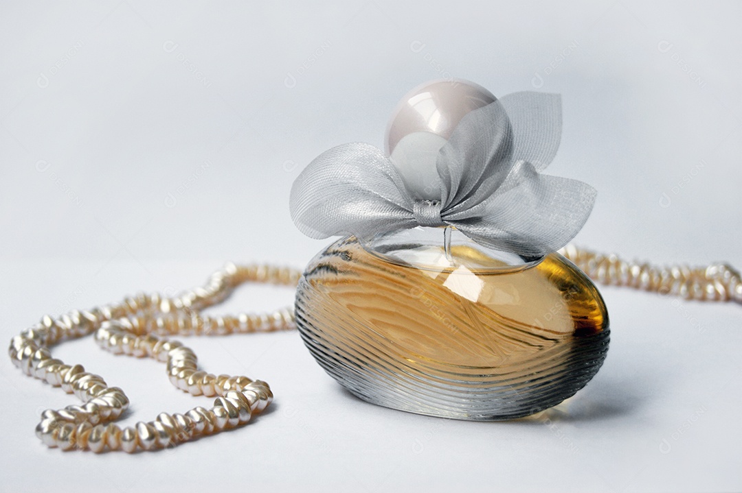 Frasco de perfume com pérolas sobre um fundo claro