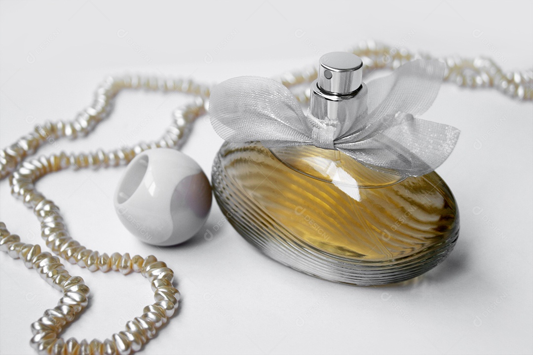 Perfume com tampa ao lado e corrente de pérolas