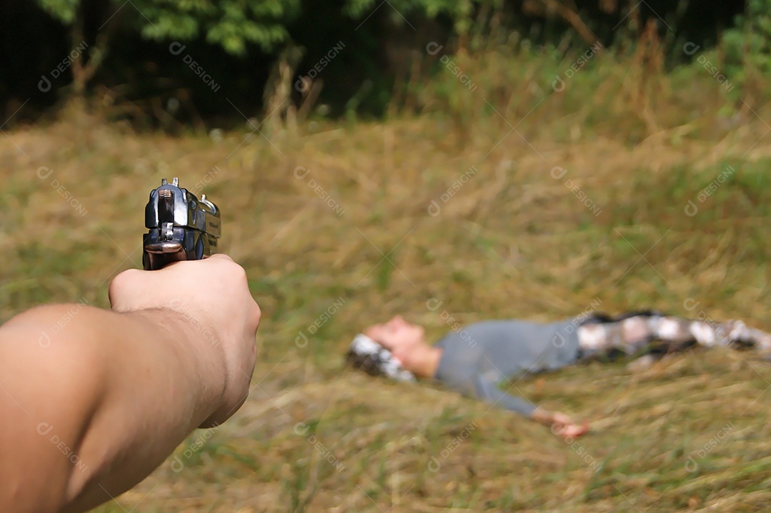 Mão com arma apontado para corpo no chão