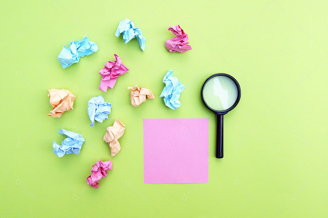 Papéis post it amassados e lupa sobre fundo verde