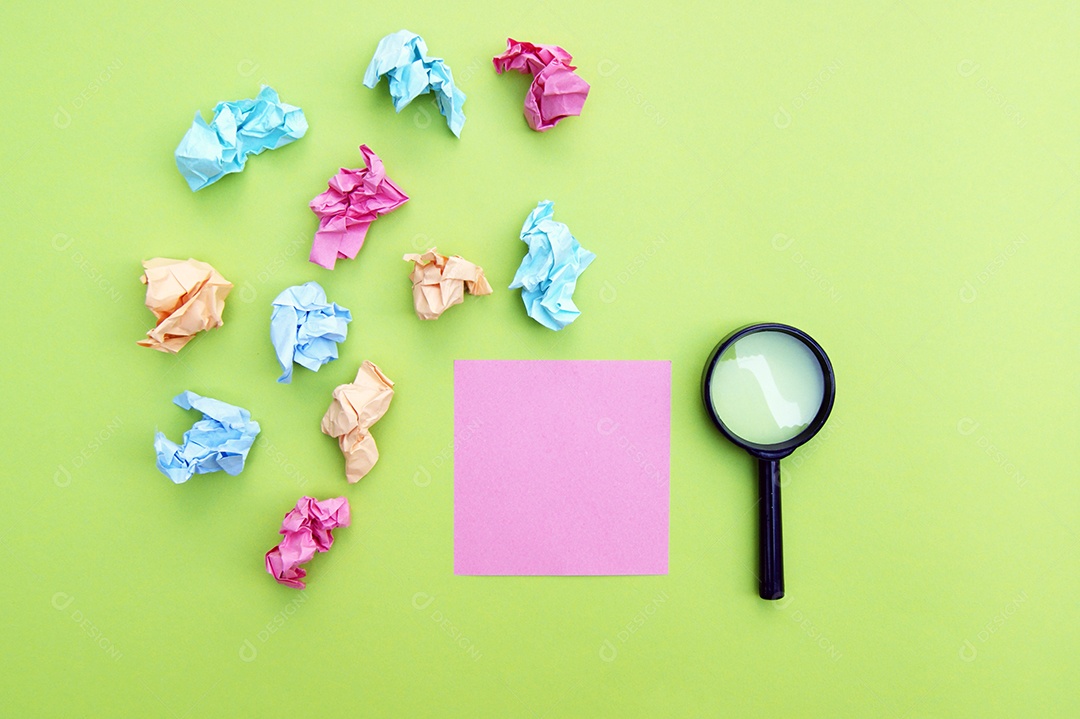 Papéis post it amassados e lupa sobre fundo verde