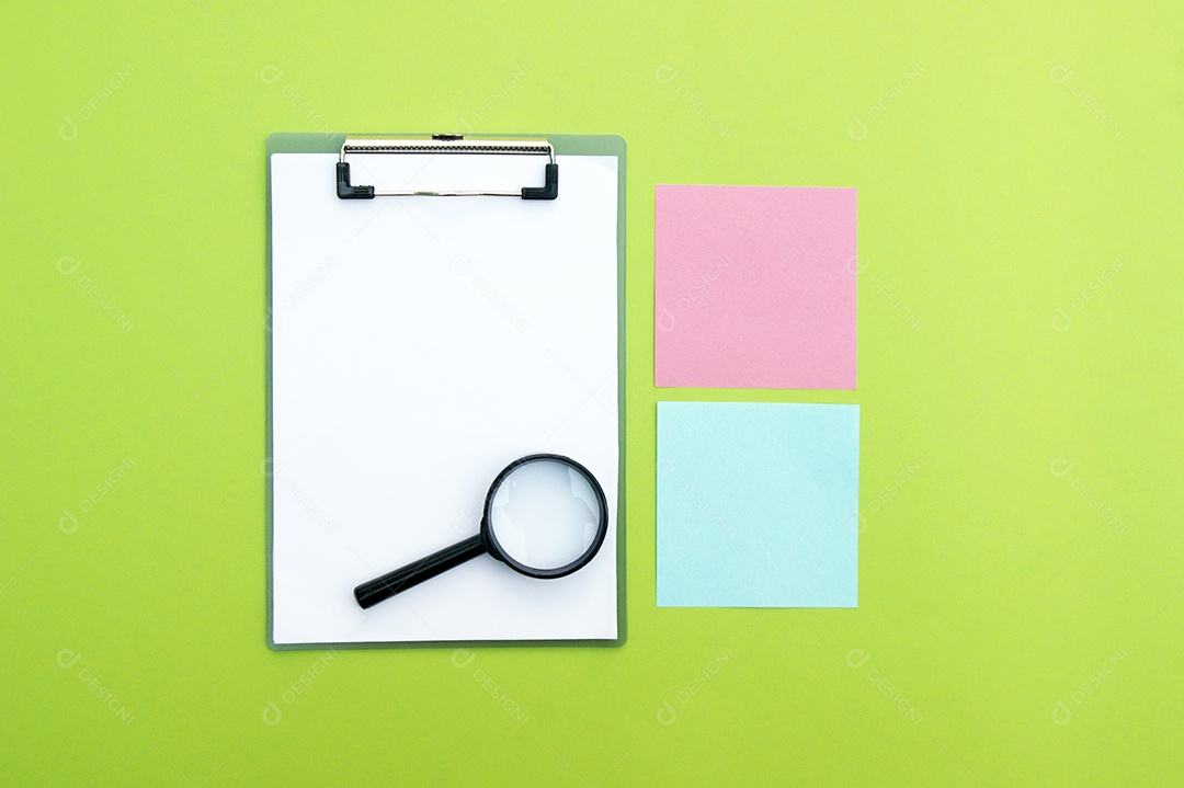 Prancheta com lupa e papéis coloridos sobre fundo verde claro