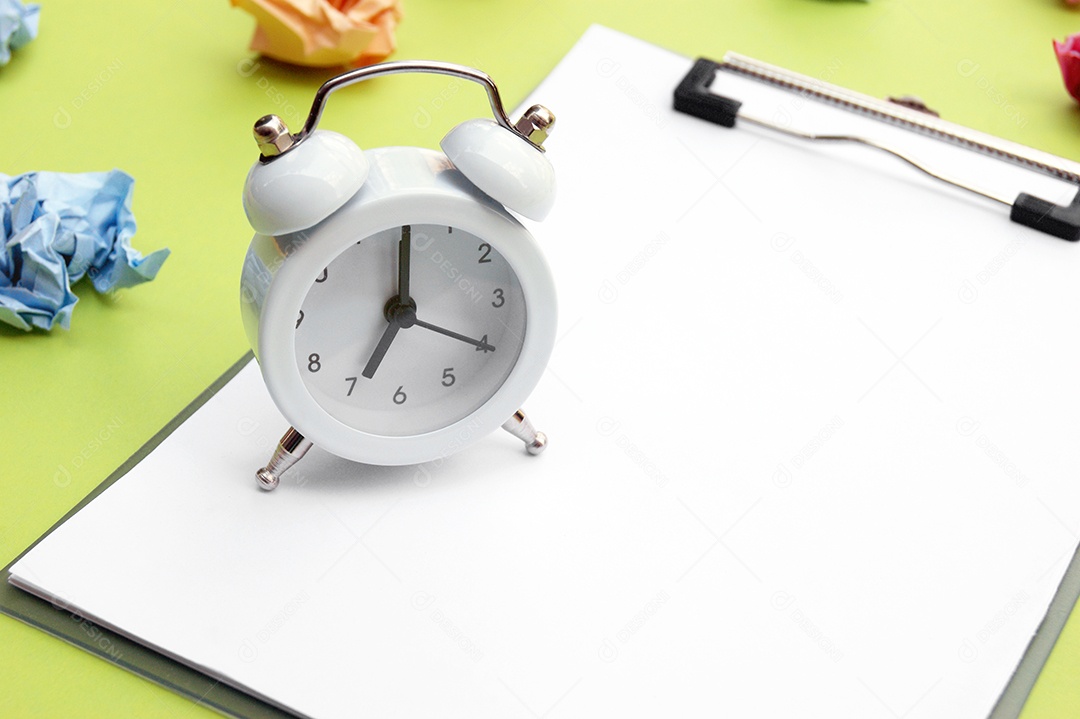 Despertador branco prancheta e papéis amassado