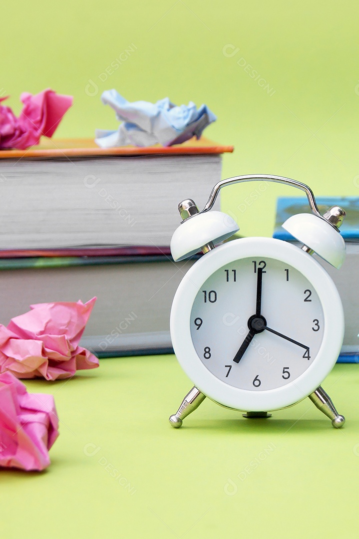 Um relógio branco marcando 7horas com livros caderno atras conceito de volta as aulas
