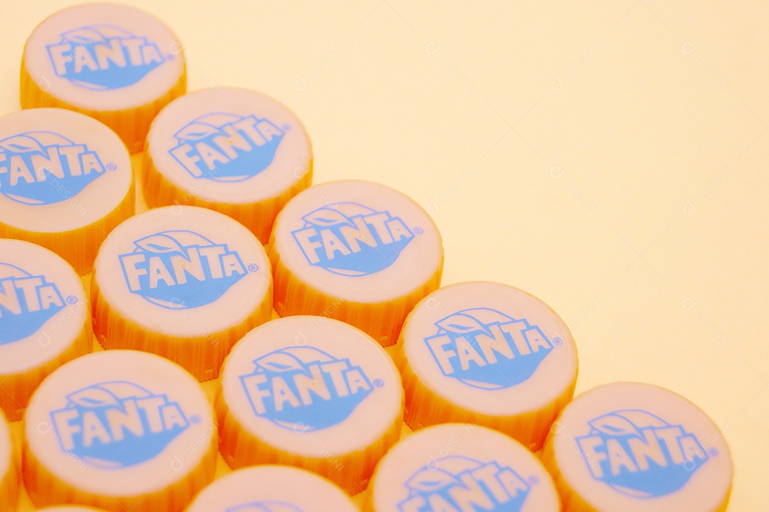Tampas de garrafa pet da Fanta sobre fundo amarelo