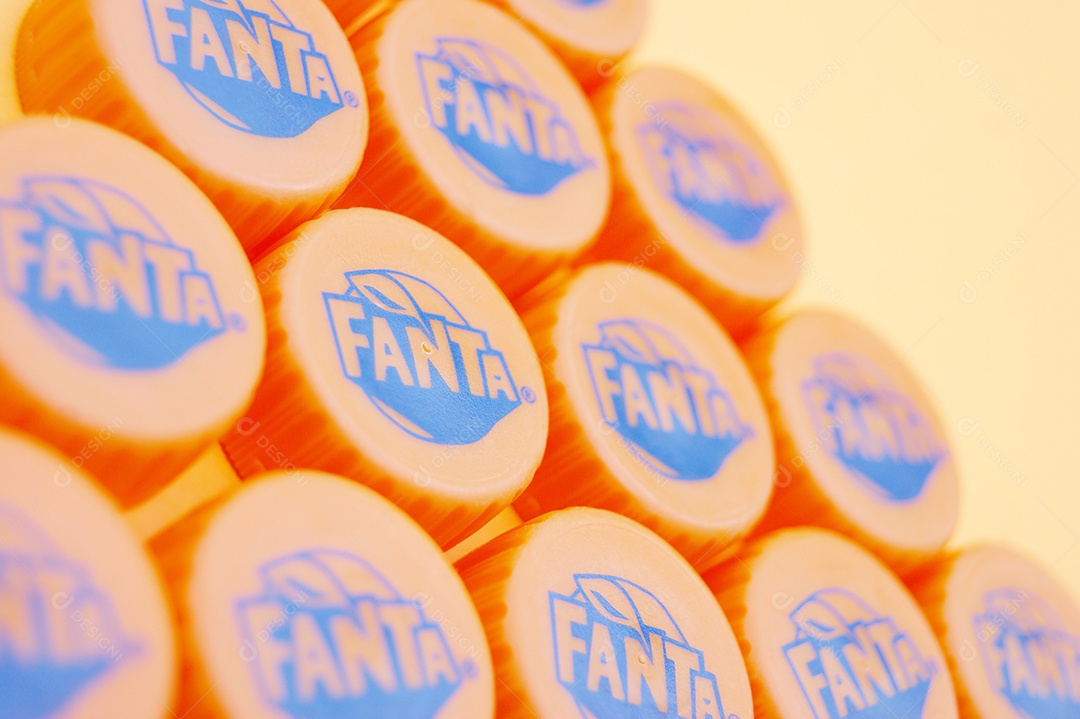 Tampas de garrafa pet da Fanta sobre fundo amarelo