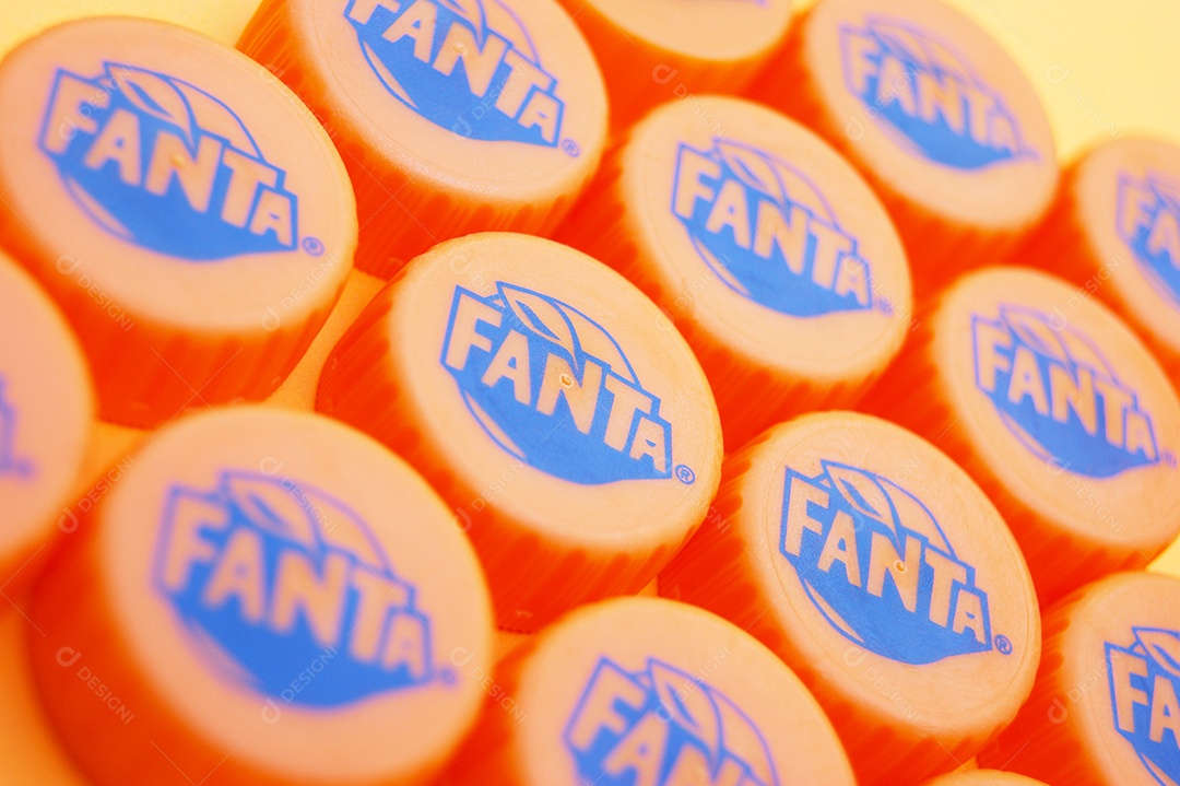 Tampas de garrafa pet da Fanta sobre fundo amarelo