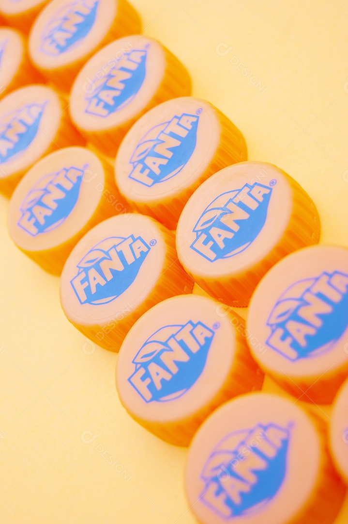 Tampas de garrafa pet da Fanta sobre fundo amarelo