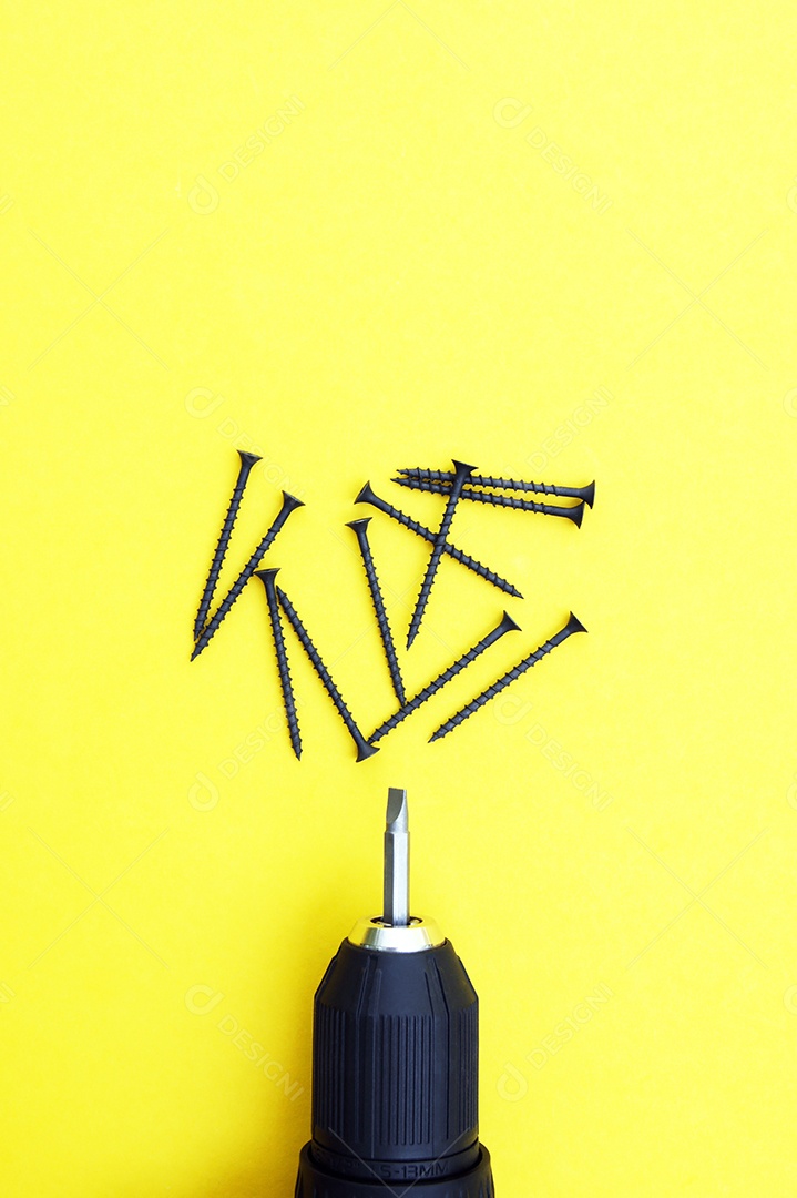 Parafusos e parafusadeira sobre fundo amarelo