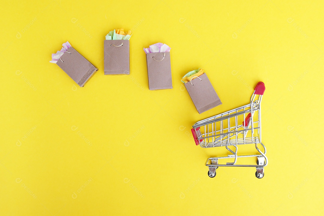 Sacolas kraft e carrinho de compra sobre fundo amarelo