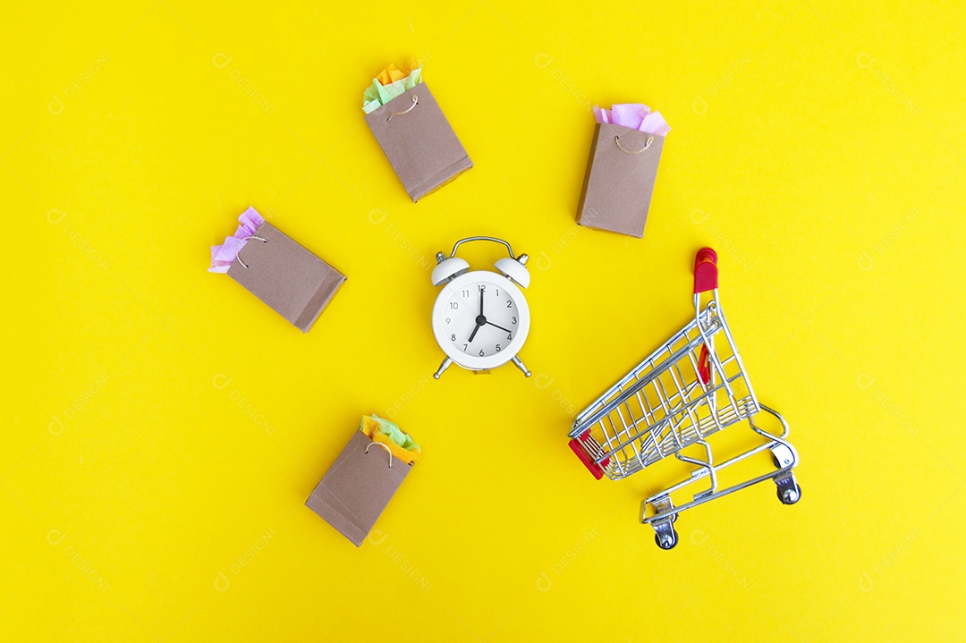 Carrinho e sacola kraft e relógio sobre fundo amarelo